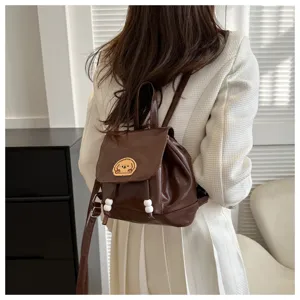 Brown mini leather backpack detail showing cute dog embroidery patch and strap bead charms.