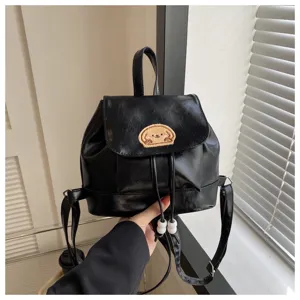 Detail view of a black PU leather backpack with a cute puppy patch and drawstring closure.
