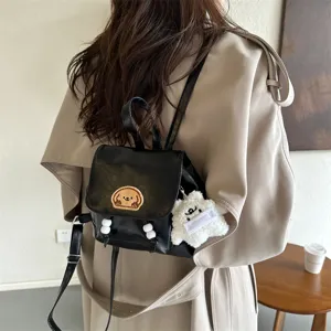 Stylish black PU leather mini backpack for women, featuring cute dog patch and plush toy charm.