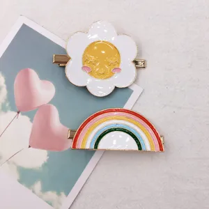 Enamel hair clip detail view featuring cute smiling sun flower and colorful rainbow design.