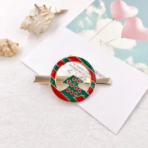 Detailed close-up of the Christmas tree hairpin, featuring vibrant red and green enamel on gold metal.