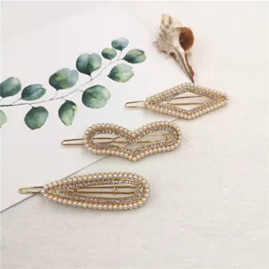 Close-up detail of three gold geometric pearl rhinestone hair clips arranged neatly on fabric.