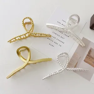 Detailed view of metal hair claws in gold and silver, featuring twisted and cross designs.