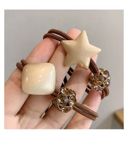 Close-up detail of stylish brown hair tie featuring elegant resin star and rhinestone bead.