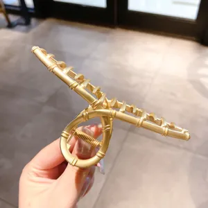 Close-up detail of the matte gold metal hair claw clip, showcasing geometric ring and teeth.
