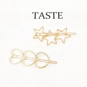 Close-up of gold metal hair clips featuring stylish star and heart geometric designs.