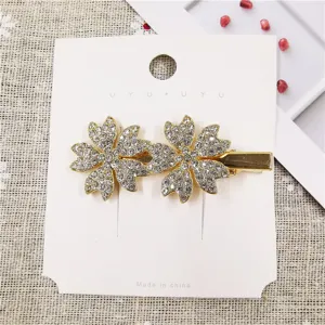 Close-up detail of elegant gold rhinestone flower hair clip, shiny crystal duckbill hairpin.
