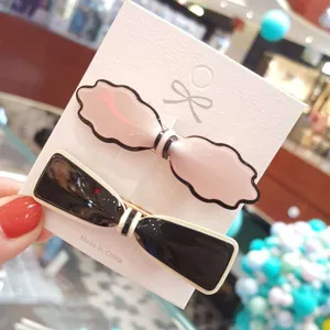 Closeup of stylish acrylic bow hair clips set on display card, elegant design for daily wear.