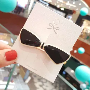 Closeup of a black and white acrylic bow hair clip on a white card, elegant accessory detail.