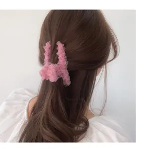 Gros plan d'une pince à cheveux en dentelle rose sur cheveux bruns, accessoire de coiffure élégant.