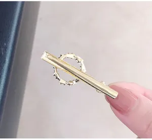 Close-up detail of a minimalist gold geometric hair clip with sparkling rhinestones.