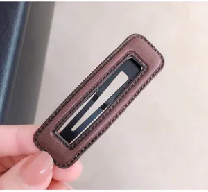 Close-up detail of a minimalist brown leather wrapped snap hair clip, elegant side fringe styling.