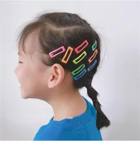 Detail shot showing colorful rectangle BB hair clips worn on a child's braided hair.