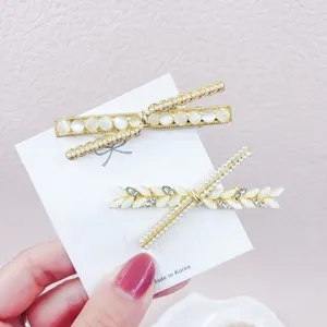 Elegant gold-tone hair clip set featuring cat eye stones and pearls for stylish women.