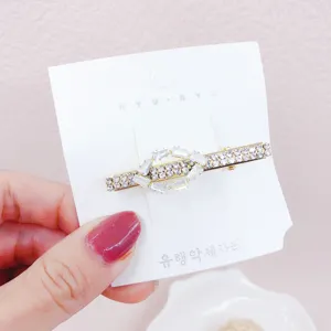 Dettaglio forcina per capelli con strass dorati, fermaglio in cristallo brillante.