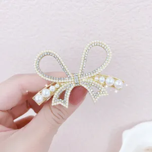 Detail shot of a stunning gold pearl rhinestone bow hair clip showcasing exquisite craftsmanship and sparkle.