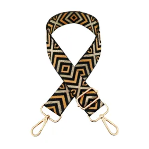 Détail de sangle de sac tissée géométrique avec fils dorés et argentés et bouclerie dorée.