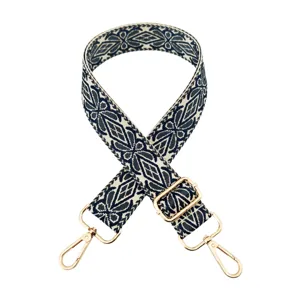 Detailed view of the wide embroidered replacement bag strap with adjustable gold hardware buckles.