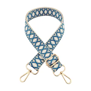Close-up details of the blue and white woven jacquard bag strap with sturdy gold metal hardware.