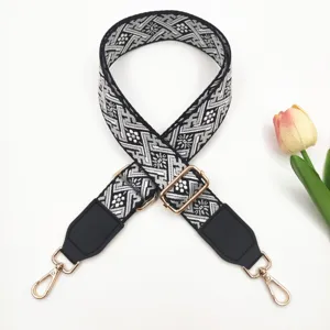 Detailaufnahme des schwarz-weißen gewebten Taschenriemens mit attraktiven goldenen Beschlägen.