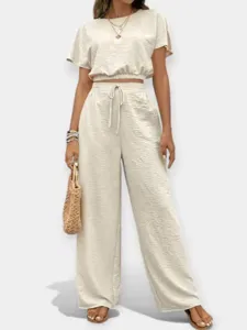 Detalle del conjunto de crop top y pantalón ancho beige con tela texturizada y corte elegante.