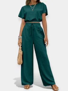 Conjunto elegante de mujer con top liso de cuello redondo y pantalones anchos altos