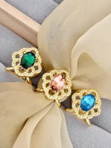 Close-up of vintage gold hollow filigree scarf ring with vibrant oval crystal details.