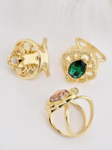 Close-up detail of vintage gold-tone hollow lace scarf ring with oval green crystal stone.