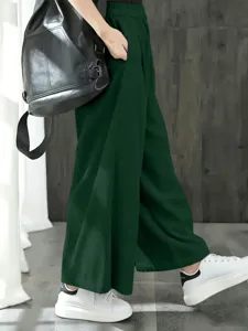 Vue rapprochée de pantalon large plissé vert foncé, détail de taille haute élastique.
