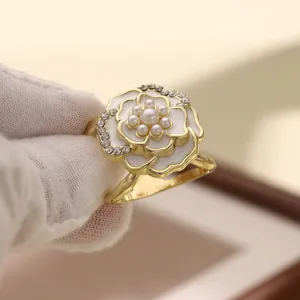 Detail shot of the elegant gold-plated camellia flower scarf buckle with pearls and rhinestones.