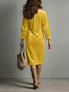 Detailweergave van een stijlvolle retro gele fluwelen midi overhemdjurk met laarzen.