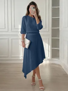 Conjunto de dos piezas azul informal con top de hombros caídos y falda midi asimétrica.