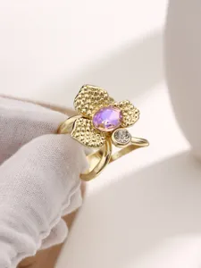 Primo piano dettagliato della fibbia per sciarpa floreale dorata con pietra viola brillante.