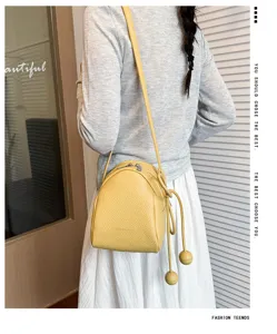 Dettaglio della borsa a tracolla gialla in pelle, elegante forma a conchiglia con coulisse a sfere.