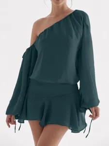 Primer plano de los detalles del vestido asimétrico de gasa verde oscuro con volantes.
