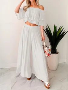 Detailed view of white off-shoulder crop top and wide-leg pants two-piece set in a modern room.