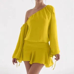 Vestido corto amarillo de gasa con un hombro descubierto y manga larga muy elegante.