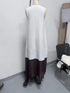 Vista detallada del vestido largo y sin mangas, con la parte superior blanca y falda marrón.