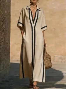 Elegante abito lungo beige con finiture a contrasto nere, colletto a risvolto e tasche.