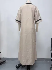 Elegante abito lungo beige con risvolto e polsini a contrasto nero per stile chic.