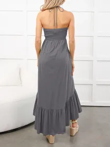 Vestido largo gris sin espalda con cuello halter, cuerpo fruncido y dobladillo con volantes.