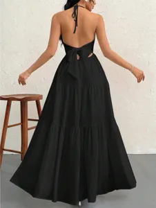Black backless halter maxi dress featuring a chic bow detail and elegant tiered flowy skirt.