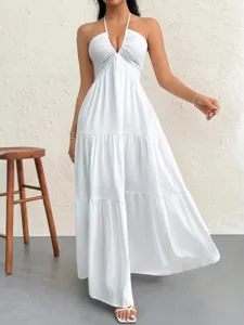 Elegant white halter neck maxi dress with deep V-neck and tiered skirt design for summer parties.