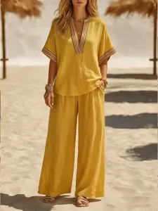 Detail view of a women casual yellow two piece outfit featuring v-neck top and wide leg pants.