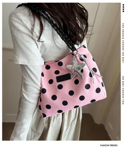 Vista dettagliata della borsa a spalla rosa a pois neri con ciondolo a stella e tracolla intrecciata.