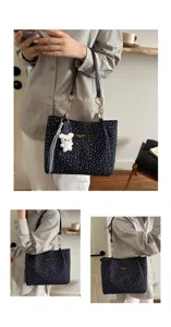 Nahaufnahme einer dunkelblauen Handtasche mit Blumenmuster und süßem Bärenanhänger.