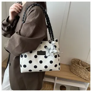 Primo piano della borsa a pois con manico intrecciato e ciondolo a stella argentata.