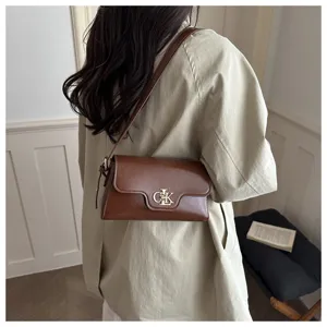 Vue détaillée d'un élégant sac à bandoulière marron avec fermoir logo en métal porté.