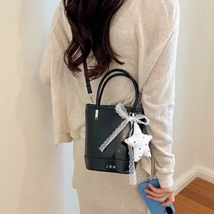 Black leather bucket bag detail view with cute lace bow and star charm, versatile design.