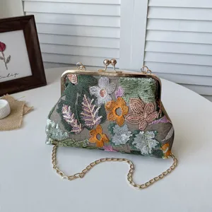 Vista detallada del elegante bolso tipo sobre bordado con flores, marco metalico y cadena.